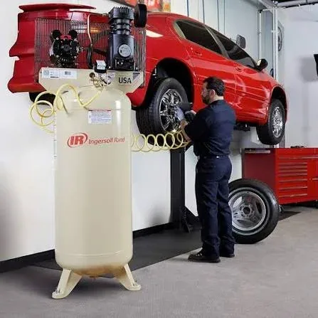 Mechanic using an Ingersoll Rand vertical piston air compressor in an automotive workshop